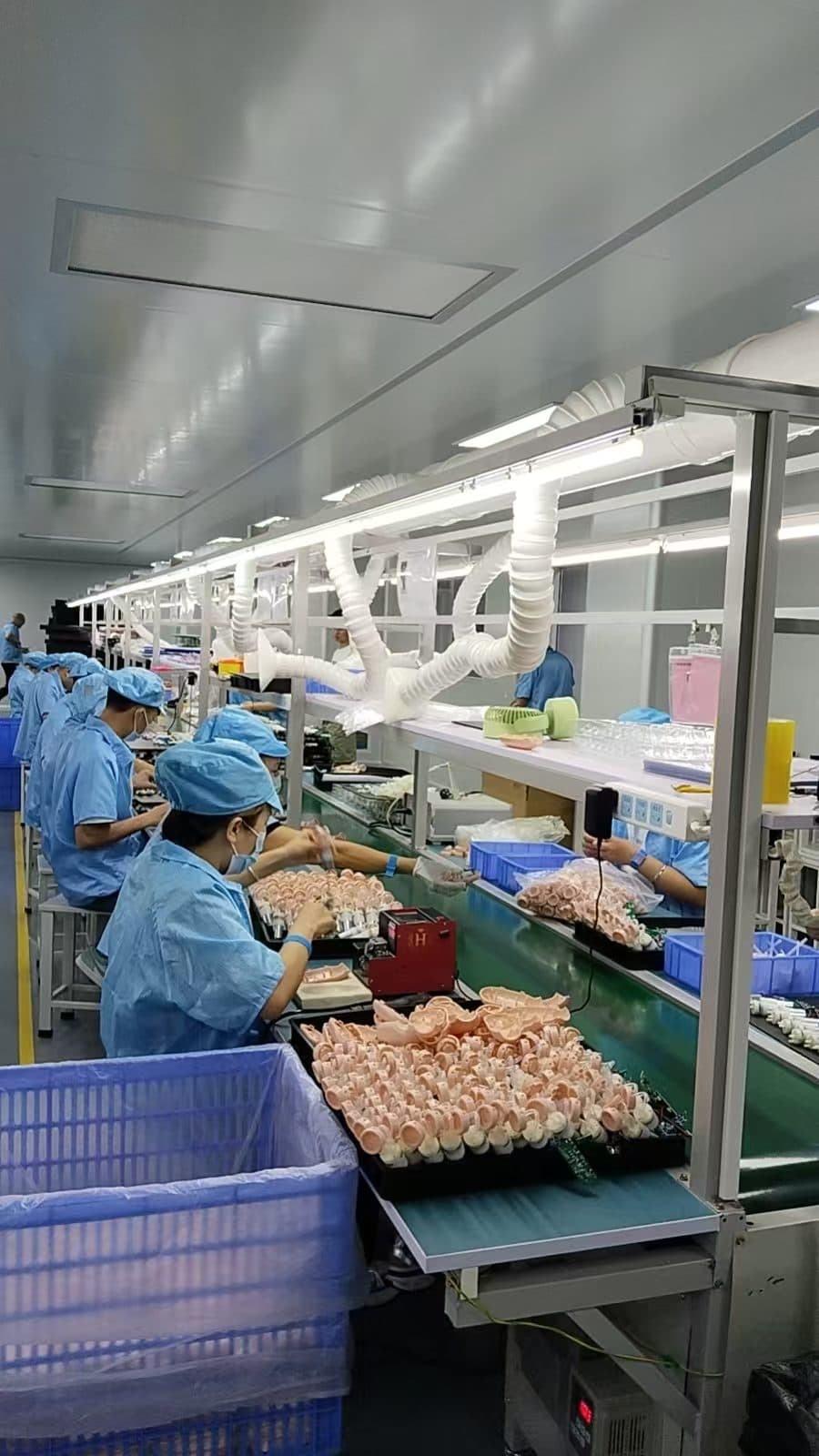 Gowned assembly workers building electric baby nasal aspirators on SiLeap's production line